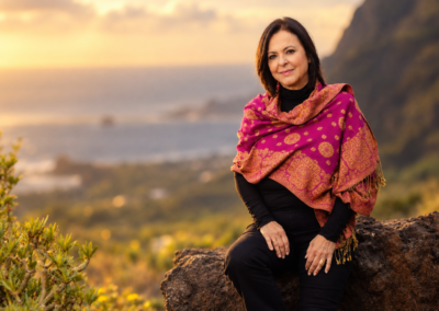 Olga Cerpa wearing a pink and orange shawl, with the coast in the background.