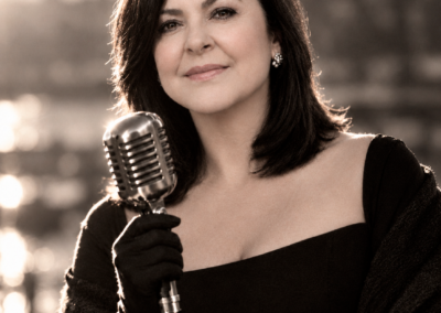 Olga Cerpa beside a vintage microphone, wearing a black dress.